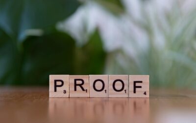 Tuiles de Scrabble en bois orthographiant « PROOF » sur une table en bois avec fond vert.