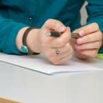 a person sitting at a table writing on a piece of paper