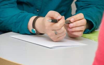 a person sitting at a table writing on a piece of paper