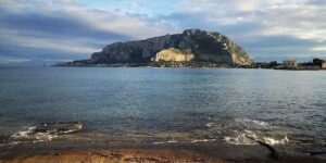 Mer calme grand rocher lointain plage sablonneuse à l'avant