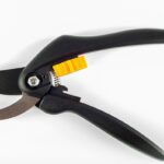 Un secateur de jardinage à main noir avec levier jaune posé